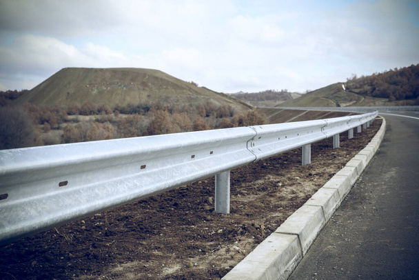 Barreira ferroviária de guarda de aço na auto-estrada sem sinal reflexivo
 - Foto, Imagem