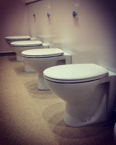 Eine Reihe von vier Toiletten vor den Kabinenwänden wird errichtet. Handy-Foto mit mobiler Nachbearbeitung. - Foto, Bild