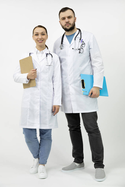 Two smart doctors man and woman in white coat standing with clipboard - Photo, Image