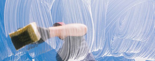 Mann mit Gummihandschuhen putzt Fenster mit Schwamm und Seife - Foto, Bild