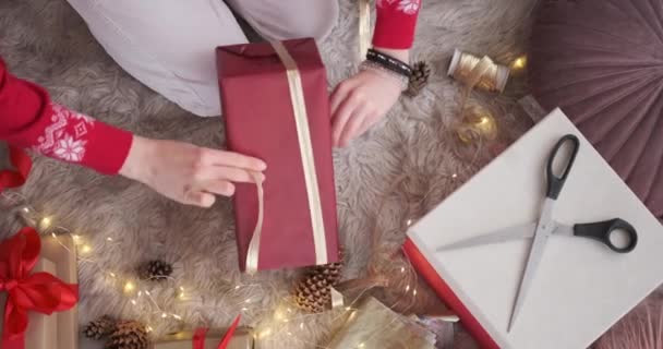 Kobieta wiąże wstążkę na Boże Narodzenie prezent - Materiał filmowy, wideo