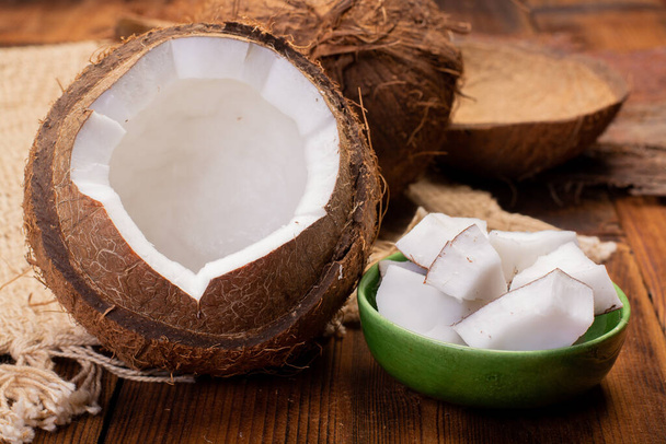 Великі тропічні пальмові горіхи кокосові і кокосові шматочки готові їсти на дерев'яному фоні крупним планом
 - Фото, зображення