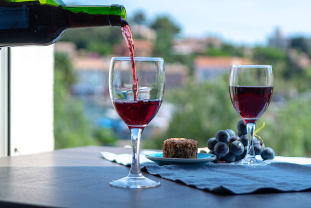 Kellner schenkt an einem sonnigen Sommertag in Frankreich Rotwein auf der Café-Außenterrasse ein - Foto, Bild