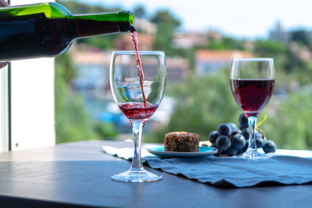 Kellner schenkt an einem sonnigen Sommertag in Frankreich Rotwein auf der Café-Außenterrasse ein - Foto, Bild
