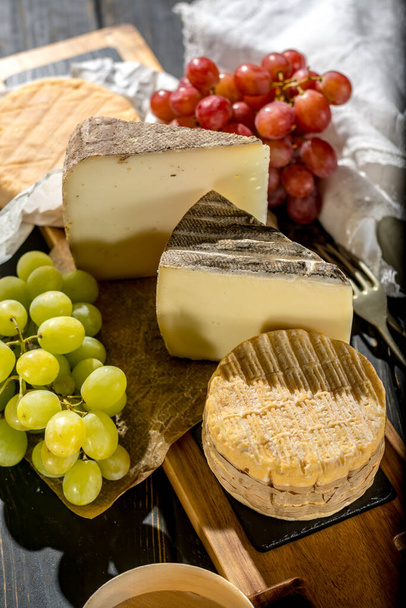 Tasting of oldest french AOC soft pudgent yellow cheese Livarot, Munster and semifirm Tomme, made from cow and goat milk french cheese close up - 写真・画像