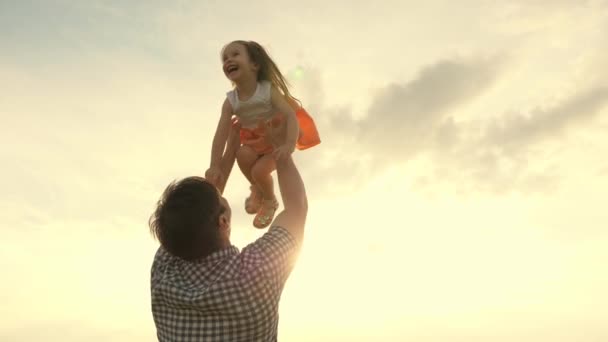 Отец и маленький ребенок играют, смеются и обнимаются вместе. Папа бросает счастливую дочь в голубое небо. Эппи семья путешествует. Ребенок на руках у родителей. Папин выходной. Концепция счастливой семьи - Кадры, видео