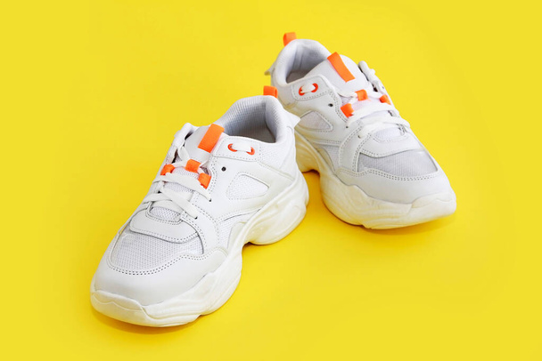 white sports shoes sneakers with laces on yellow background - Foto, afbeelding