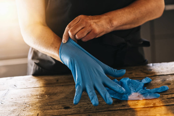 bartender or employee wearing a medical Latex gloves at work to prevent Coronavirus corona virus covid 19 infection. - Фото, зображення