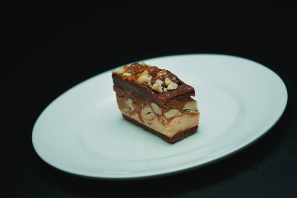 brownie cake piece with peanuts on a white plate - Zdjęcie, obraz