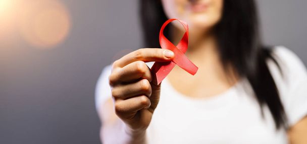 Woman with red AIDS or HIV ribbon. Breast cancer awareness concept  - Photo, Image