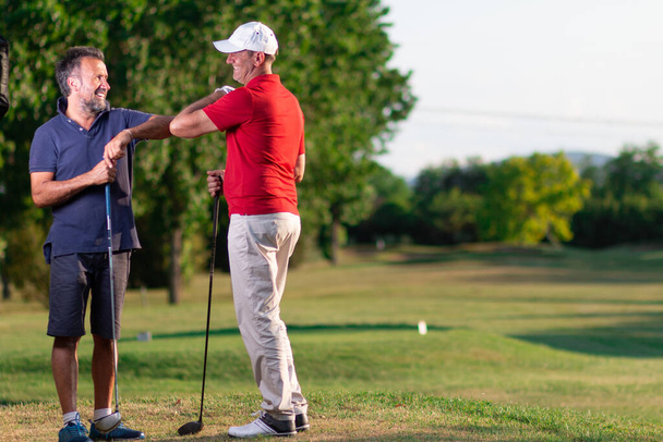 zwei Golfer begrüßen sich, indem sie ihre Ellbogen berühren - Golffreunde grüßen zur Zeit des Covides - Foto, Bild