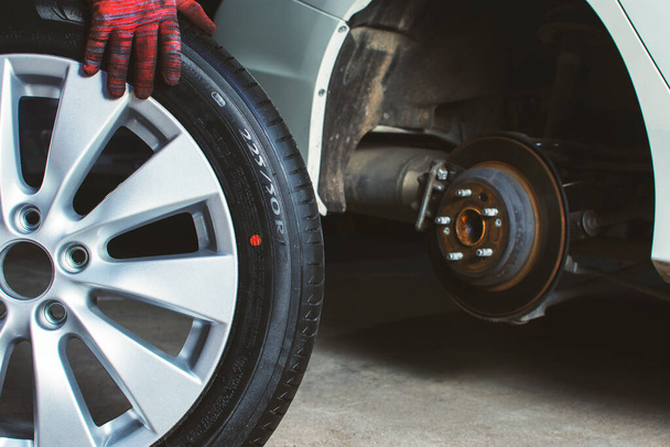 Mécanicien automobile pousse les roues en alliage à installer dans le moyeu de roue dans l'atelier de réparation de véhicules
. - Photo, image