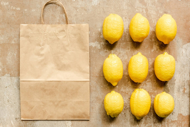flat lay with lemons near paper bag on weathered surface - Photo, Image