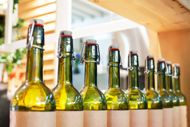 Зелені скляні пляшки вина в лінії на дерев'яній полиці, дизайн інтер'єру барів, ілюстрація алкогольних коктейлів, концепція дегустації вина, стиль нічного життя, виробництво вин, розмитий фон крупним планом
 - Фото, зображення