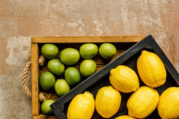 pohled shora na citrony a citrony v dřevěných krabicích na ošlehaném povrchu - Fotografie, Obrázek