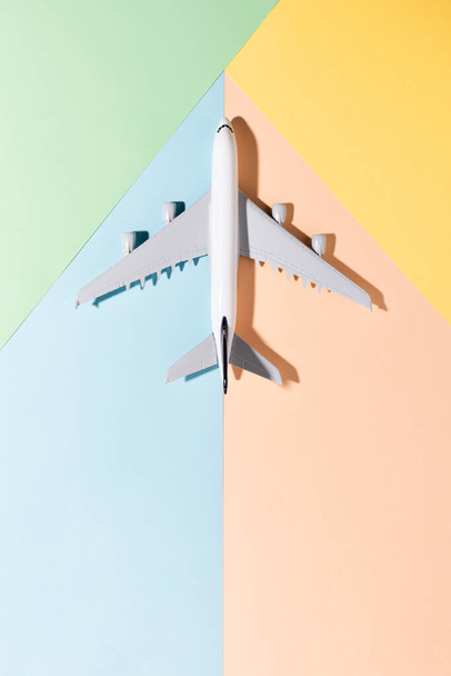 Model samolotu na jasnoniebieskim, pomarańczowym, zielonym, żółtym tle papierowym. Płaskie ułożenie, widok z góry i kopiowanie miejsca na tekst - Zdjęcie, obraz