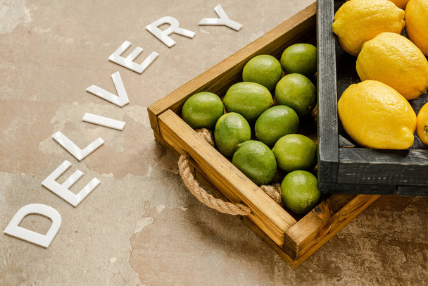 limones maduros y limas en cajas de madera cerca de la entrega de la palabra en la superficie erosionada
 - Foto, Imagen
