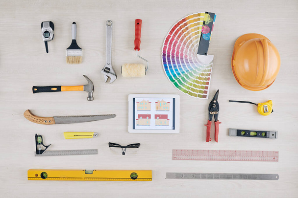Tablette avec photo de la maison sur la table avec outils de construction, casque et palette de couleurs - Photo, image