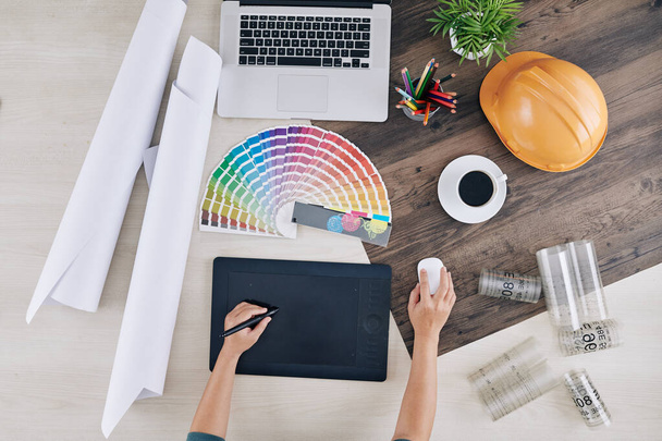 Návrhář interiérů pracující na grafickém tabletu u stolu s barevnou paletou, modrotisky a šálkem kávy, pohled shora - Fotografie, Obrázek