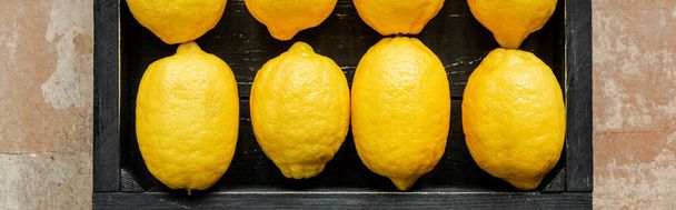 top view of lemons in wooden black box on weathered surface, panoramic crop - Foto, imagen