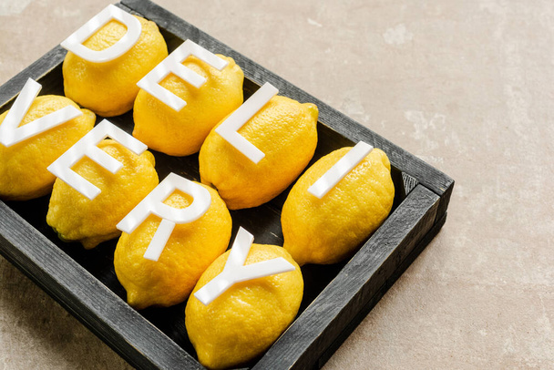 word delivery on lemons in wooden black box on weathered surface - Photo, Image