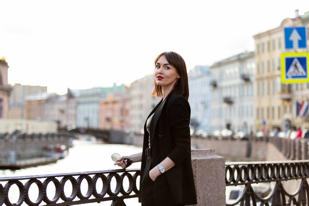 Beautiful woman in black pantsuit walks on promenade in Saint-Petersburg - Foto, immagini