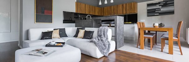 Panorama of elegant apartment with kitchen with dining area open to living room with big white corner sofa - Photo, image