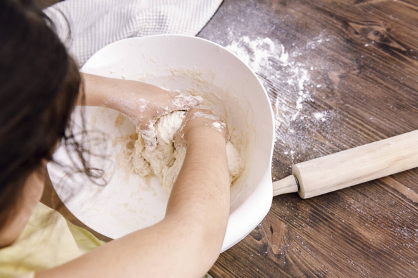 onherkenbaar klein meisje het maken van zelfgemaakt brood deeg, gezond voedsel concept thuis - Foto, afbeelding