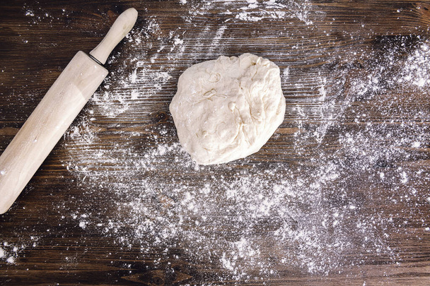 ciasto chlebowe obok wałka na drewnianym stole pełnym mąki, koncepcja zdrowej żywności domowej roboty - Zdjęcie, obraz