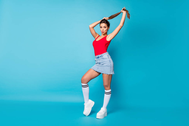 Full size photo of stunning chic girl send air kiss prepare for 14-february date hold hand make ponytail hairstyle wear red legs tank-top white singlet isolated over blue color background - Фото, зображення