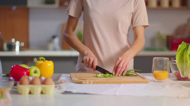 Femme coupant des oignons sur une planche en bois à la cuisine. Femme au foyer préparant la salade
 - Photo, image