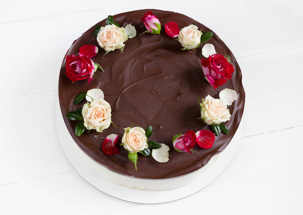 Chocolate cake with roses. Birds milk Cake.  Beautiful cake with red and white rose flowers. White  background, empty space - Photo, Image