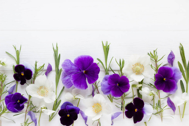 Flores de diseño plano. Composición floral, flores violetas y blancas. Plantilla con espacio de copia sobre tabla de madera blanca. Flores de viola y anémona
 - Foto, Imagen