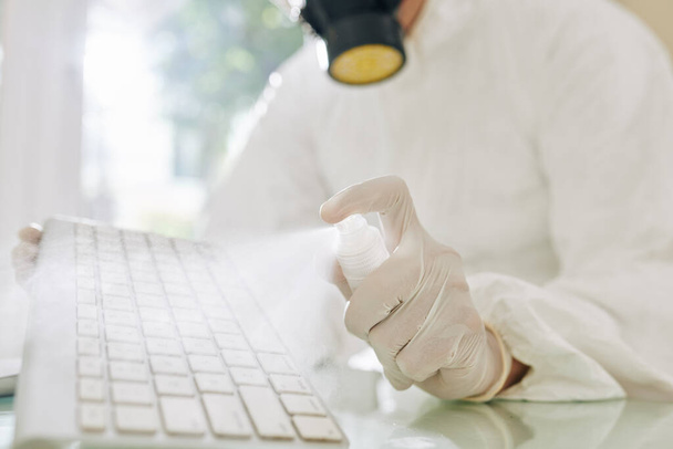 technicien pulvérisation fréquemment touché clavier d'ordinateur avec un détergent de nettoyage pour tuer le virus covid-19 - Photo, image