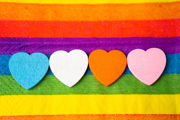 Wooden hearts on LGBT rainbow colorful cloth, a symbol of lesbian, gay, bisexual, transgender, human rights, tolerance and peace. - Photo, Image