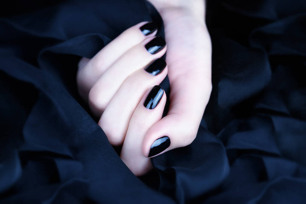 Female hand with black manicure on a black background - Photo, Image