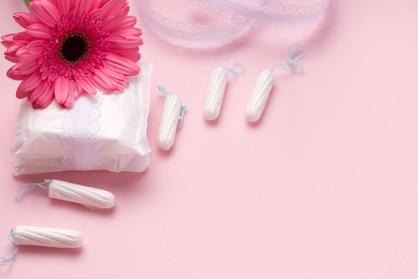 Концепция менструального цикла у женщин. Тампоны и прокладки рядом с цветком на розовом фоне. Копирование пространства
 - Фото, изображение