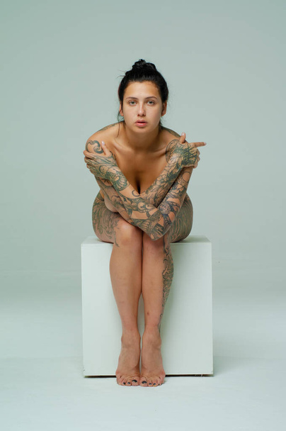 young beautiful girl posing nude in the studio, sedit on a cube - Φωτογραφία, εικόνα