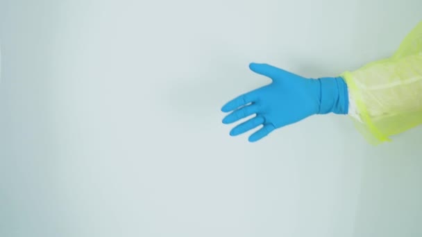 Due medici indossano tute protettive dal virus della corona infezione covid-19, guanti di gomma medica blu. La gente si saluta, si tiene per mano su sfondo bianco di reparto ospedaliero. Gesto di proibizione - Filmati, video