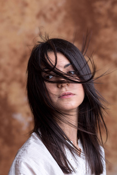 portrait of beautiful dark-haired girl with long hair blowing in the wind. High quality pportrait of beautiful dark-haired girl with long hair blowing in the windhoto - Fotoğraf, Görsel