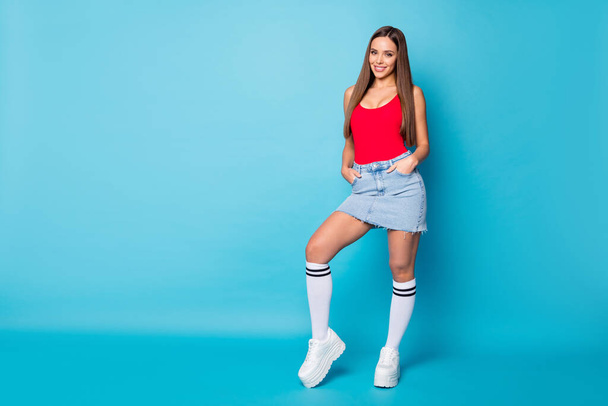 Full size photo of pretty content girlish girl enjoy spring free time weekend put hands pockets wear good look clothes singlet isolated over blue color background - Foto, immagini