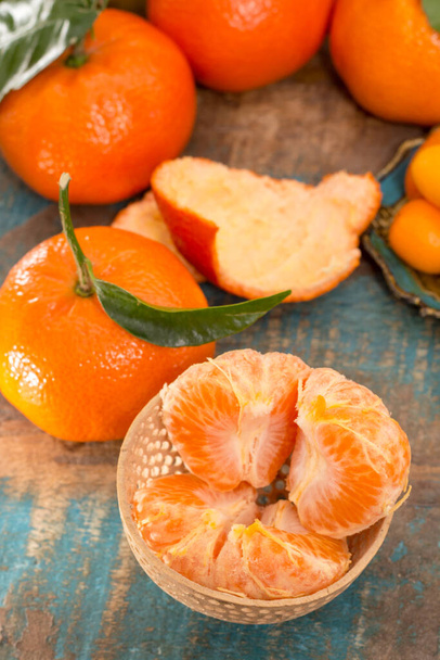 Dojrzałe tropikalne owoce cytrusowe, mandarynki lub klementynki z bliska na niebieskim drewnianym stole - Zdjęcie, obraz