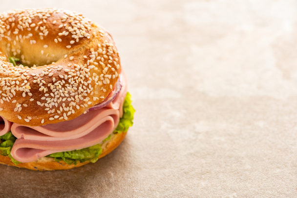 fresh delicious bagel with sausage on textured surface - Photo, image