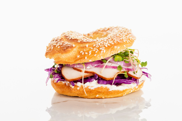 fresh delicious bagel with meat, red onion, cream cheese and sprouts on white background - Foto, Imagen