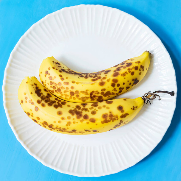 Banana cavendish matura con macchie marroni su piatto bianco
 - Foto, immagini