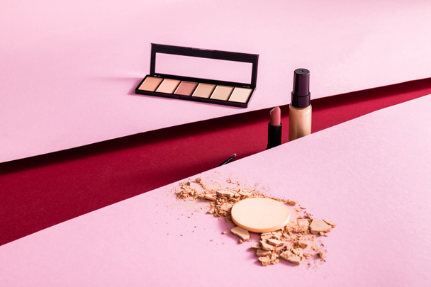 makeup foundation, eye shadow, lipstick and cosmetic brush near face powder on pink and crimson  - Φωτογραφία, εικόνα