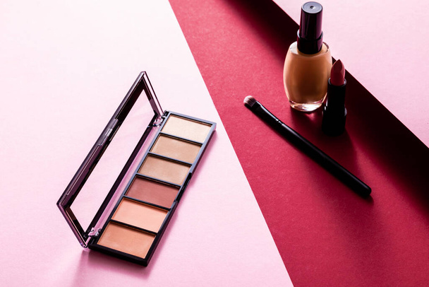 makeup foundation, eye shadow, cosmetic brush and lipstick on pink and crimson  - Zdjęcie, obraz