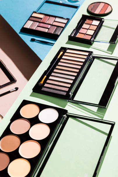 selective focus of eye shadow and blush palettes on green, blue and pink  - Foto, afbeelding