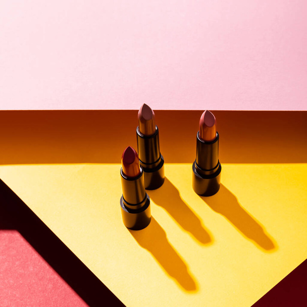 primer plano de los lápices labiales en amarillo, carmesí y rosa
  - Foto, Imagen