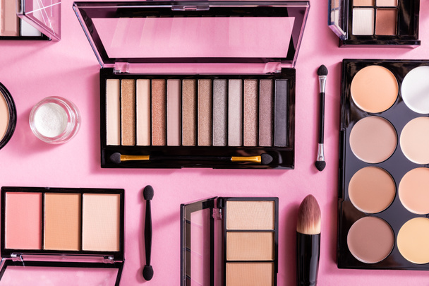 top view of eye shadow and blush palettes near cosmetic brushes on pink  - Foto, Imagem